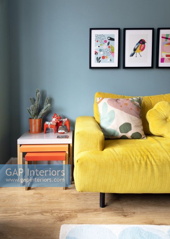 Canapé jaune et tables gigognes orange dans un salon coloré