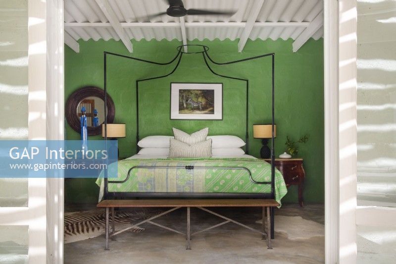 Chambre avec lit à baldaquin en métal et mur végétal