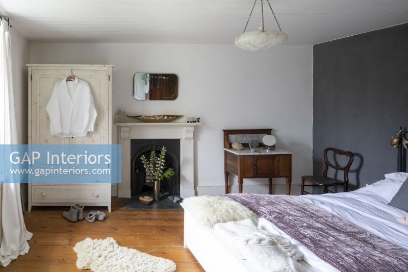Une chambre de campagne luxueuse et douce avec une armoire, un lit recouvert d'un jeté violet et un lavabo en marbre.