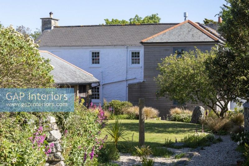 Maison de Sally et John Biddle à Cornwall, l'extérieur montrant un joli jardin d'été avec des granges et une maison en pierre