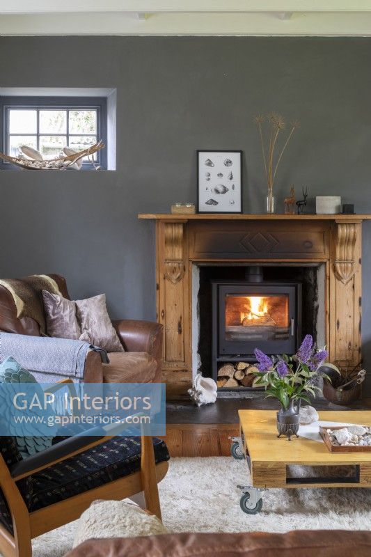 Maison de Sally et John Biddle à Cornwall, salon gris et blanc avec poêle à bois et meubles du milieu du siècle