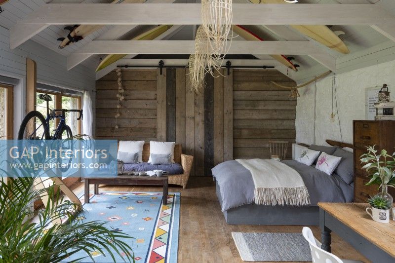 Grange aménagée, avec lit, canapé et poutres en bois à la décoration rustique.