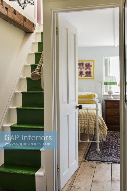 Vue sur une chambre de style vintage depuis le palier avec des escaliers peints en vert