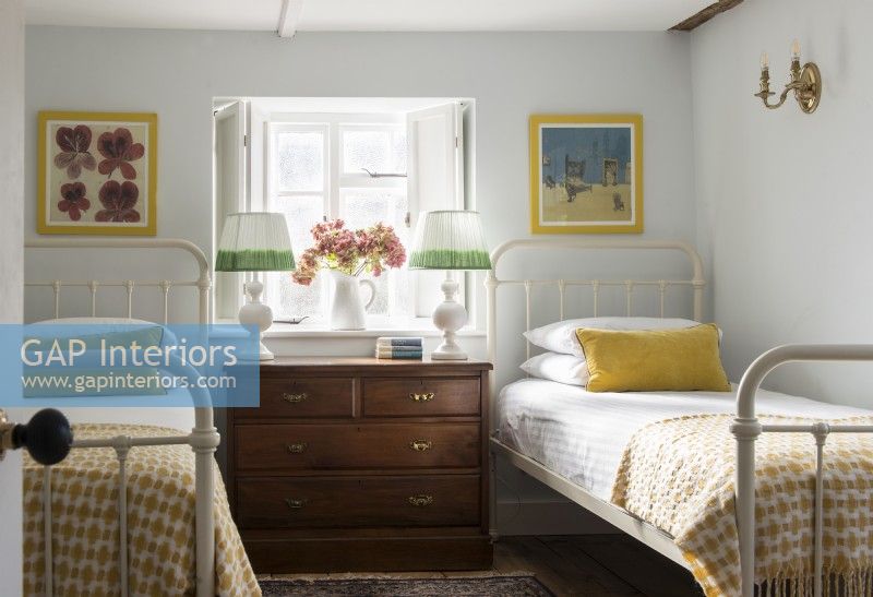 Mobilier vintage dans une chambre de campagne avec lits jumeaux à ossature métallique