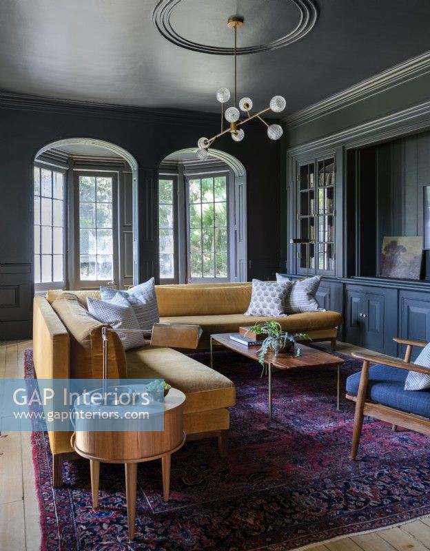 Canapé moutarde dans un salon de style classique peint en gris foncé 