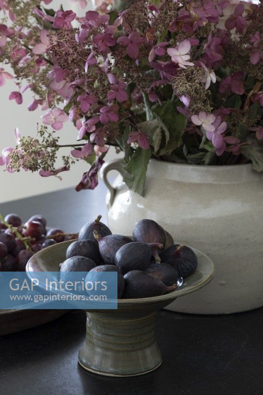 Bol de figues fraîches à côté d'un arrangement floral dans un pot en céramique 