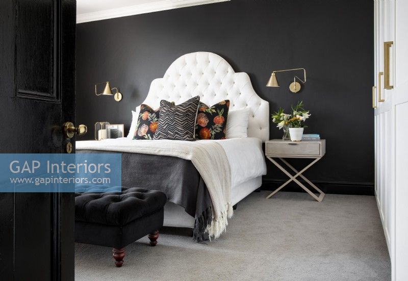 Dramatic bedroom with black walls and white deep buttoned headboard
