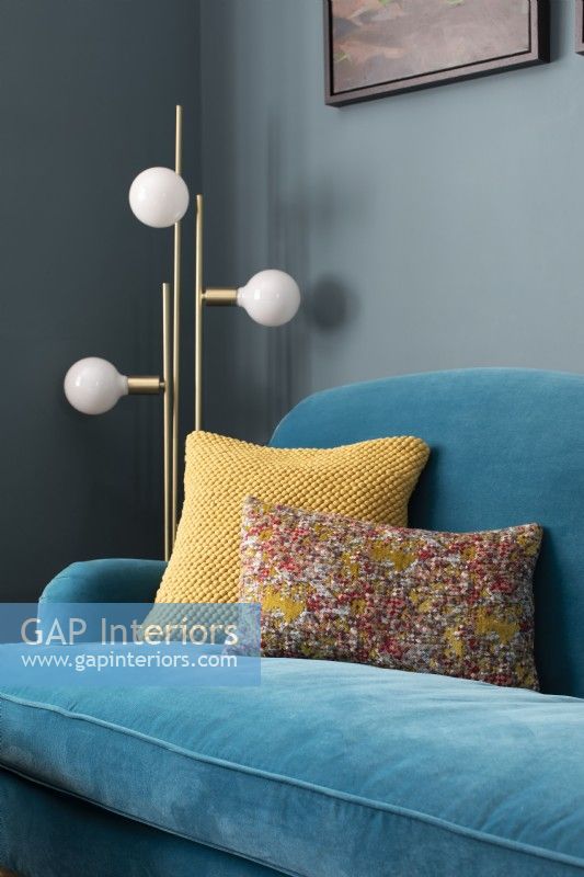 Détail de coussins colorés sur un canapé en velours bleu 