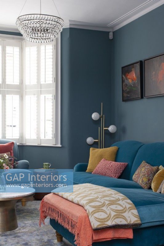 Coin salon audacieux avec murs bleu foncé et canapé en velours 
