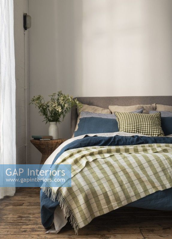 Couverture à carreaux verts sur lit double avec draps bleus 