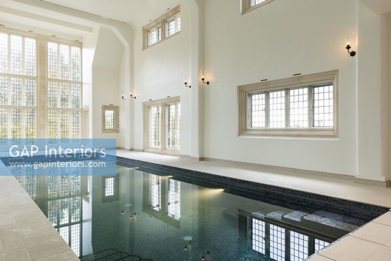 Grande piscine intérieure dans un bâtiment traditionnel avec baie vitrée. 