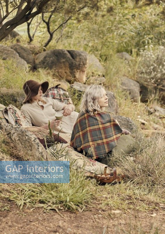 Deux femmes assises sur une couverture en zone rurale avec panier pique-nique 