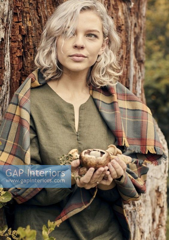 Jeune femme tenant des champignons dans les bois 