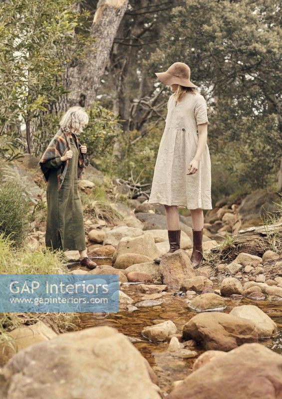 Deux femmes en vêtements vintage marchant sur des rochers dans un ruisseau 