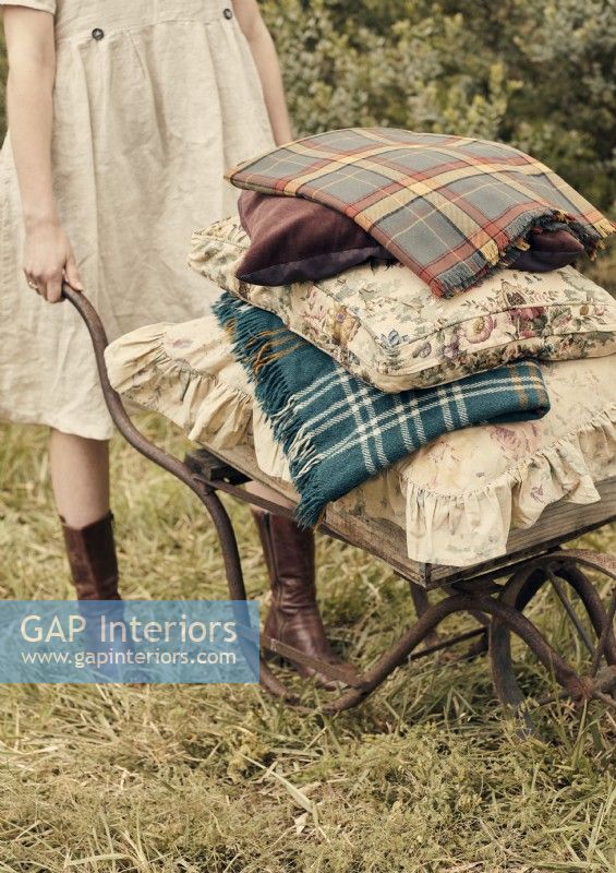 Woman with antique wheelbarrow filled with cushions and blankets