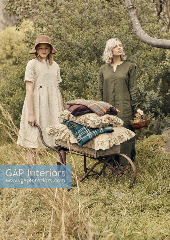Deux femmes dans le jardin avec des coussins sur une brouette antique 