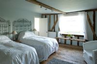 Ferme Boonshill, East Sussex. Intérieur de la chambre d'amis avec couvre-lits en dentelle antique et portes métalliques comme têtes de lit.