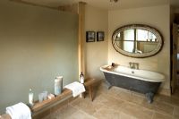 Ferme Boonshill, East Sussex. Intérieur de salle de bain avec baignoire sur pieds, banc en bois d'Inde et miroir fabriqué à partir d'une vieille fenêtre.