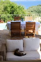 Corfou, Grèce. Yialiskari House Villa près de Kalami. Terrasse avec chaises longues en osier, chat, table et vue sur les montagnes albanaises