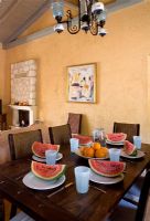 Corfou, Grèce. Malama House près de Barbati. Salle à manger avec table et chaises pour dîner. melons d'eau sur table