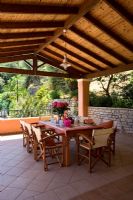 Villa Christina, Kaminaki, Corfou, Grèce. Terrasse couverte avec coin repas et table en bois et chaises pour dîner en plein air