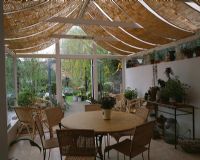 Vue du jardin d'hiver avec stores de toit et table à manger et vue sur le jardin