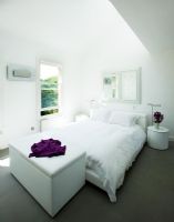Chambre moderne blanche avec lit, boîte de couverture et table de chevet avec vase de stocks