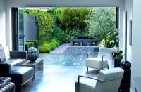 Salon moderne avec vue sur patio et petit jardin contemporain dessiné par charlotte rowe