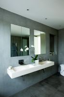 Salle de bain contemporaine élégante avec double évier mural en pierre, murs en ardoise grise, miroirs et orchidée blanche