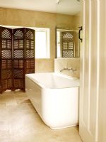 Salle de bain moderne avec baignoire, grands carreaux de grès et paravent en bois