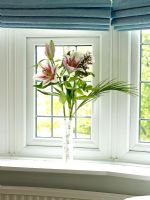 Détails d'un vase contenant des lys sur une fenêtre