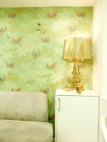 Détail du coin salon avec lampe dorée et papier peint à motifs verts