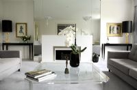Salon classique avec table basse en verre et miroir en verre pleine longueur derrière la cheminée