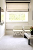 Salon blanc moderne avec fauteuils et fenêtre avec store romain crème