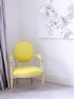 Salon avec chaise jaune rembourrée classique et art abstrait sur le mur