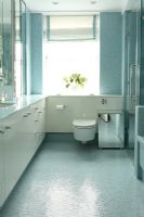 Salle de bain moderne avec rangement intégré et murs et sol en mosaïque bleue