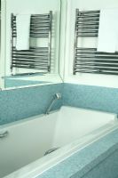 Salle de bain moderne avec des carreaux de mosaïque bleue et une serviette suspendue à un radiateur sèche-serviettes