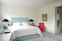Chambre classique avec lit double, lampes jumelles sur des tables de chevet en miroir, tête de lit rembourrée et chaise de style français