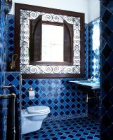 Salle de bain originale avec des carreaux bleus et une grande armoire ornée