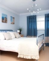 Chambre moderne avec lit double, lustre et rideaux bleus