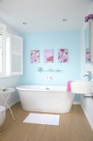 Salle de bain moderne avec murs peints en bleu, baignoire îlot et parquet