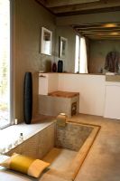 Salle de bain rustique avec murs et sol en béton et baignoire encastrée