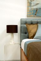 Détail de la chambre moderne avec coussins sur lit et table d'appoint avec lampe