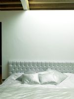 Chambre blanche moderne avec tête de lit rembourrée et ameublement
