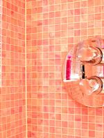 Détail de la douche sur les murs carrelés de mosaïque rose