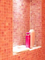 Détail de l'étagère de la salle de bain avec des murs carrelés de mosaïque rose