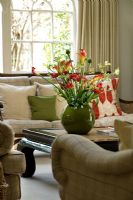 Salon avec belle exposition de fleurs - Lys calla, renoncule, tulipes et patte de kangourou dans un récipient vert