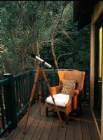 Petit balcon en bois avec un fauteuil et un télescope