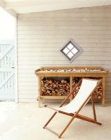 Chaise pliante sur un patio avec une pile de bois