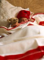 Enfant avec un jouet en peluche se cachant sous une couverture